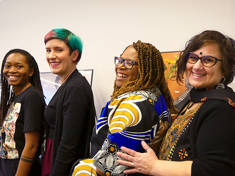 Four people standing in a row smiling